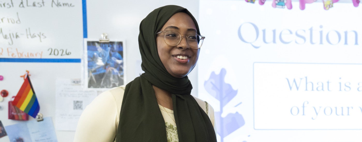 Student teacher standing in classroom with whiteboard behind