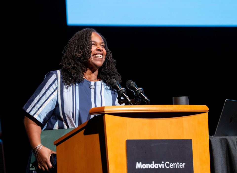 Renée Watson stands at a podium and smiles while speaking into a microphone. A sign on the podium reads "Mondavi Center."