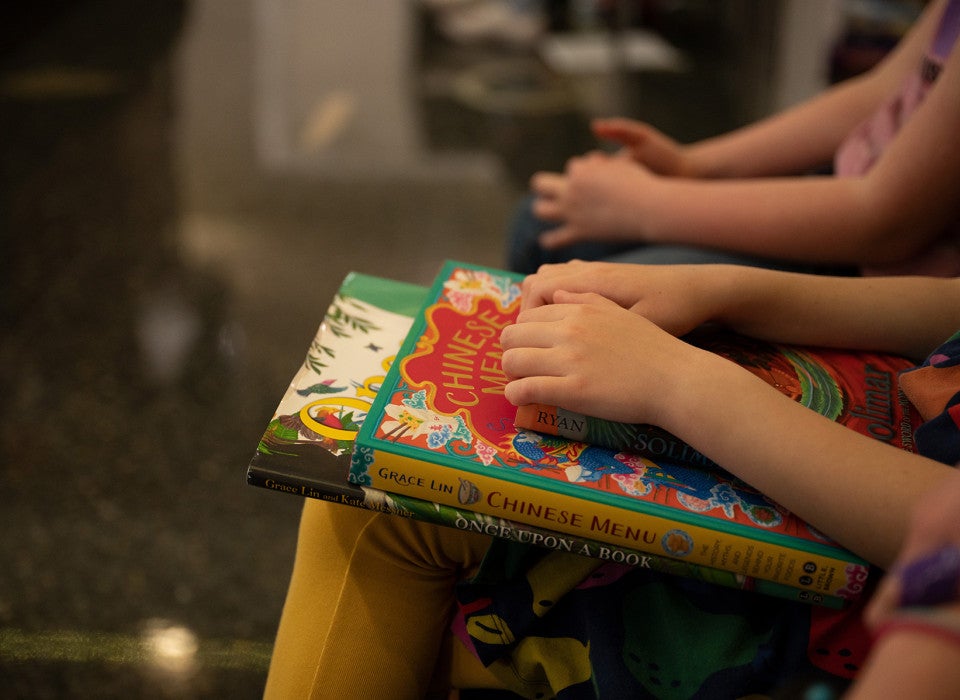 Two children's books sit in a young student's lap.